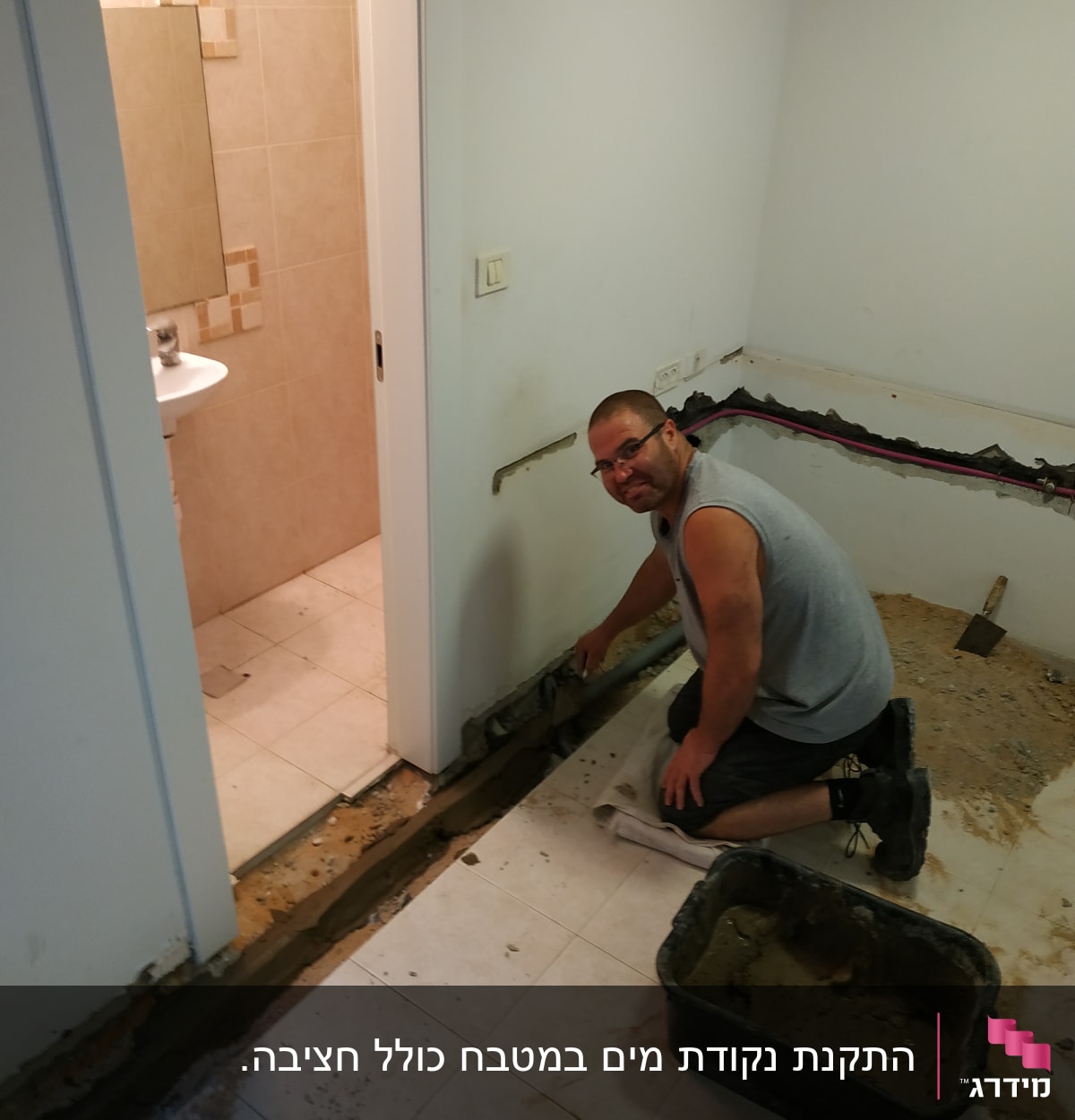 אדם עובד על צינור מים בקיר חדר אמבטיה